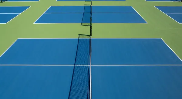 Well-maintained pickleball courts with clear white line markings, regulation dimensions, and net showing proper court spacing
